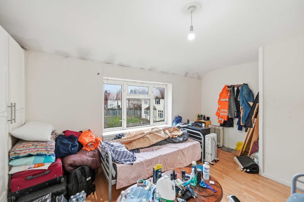 Bedroom piled with clutter, bags and belongings before cleanup