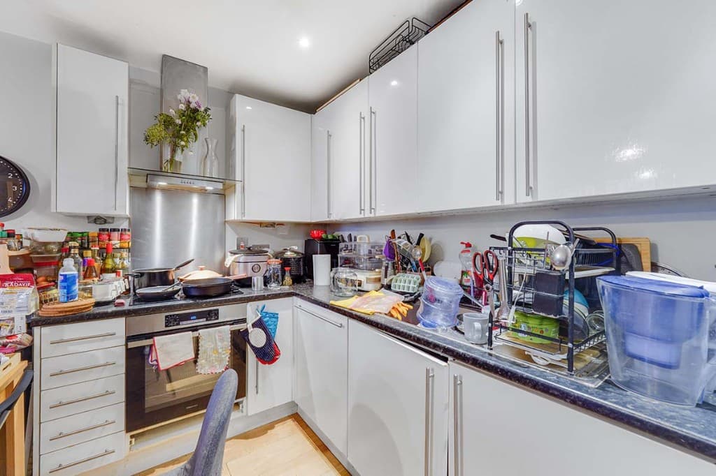 Kitchen worktops cluttered with appliances and utensils before cleanup